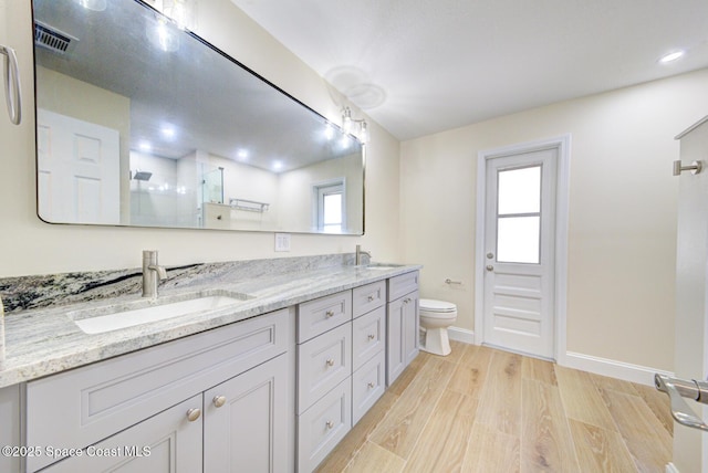 full bath featuring a sink, toilet, wood finished floors, and a shower stall