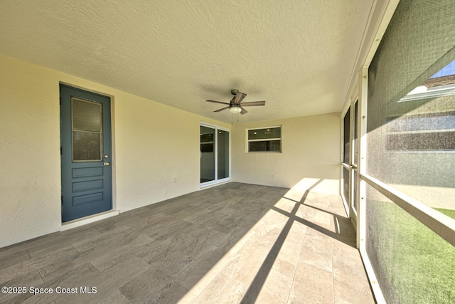 unfurnished sunroom with ceiling fan