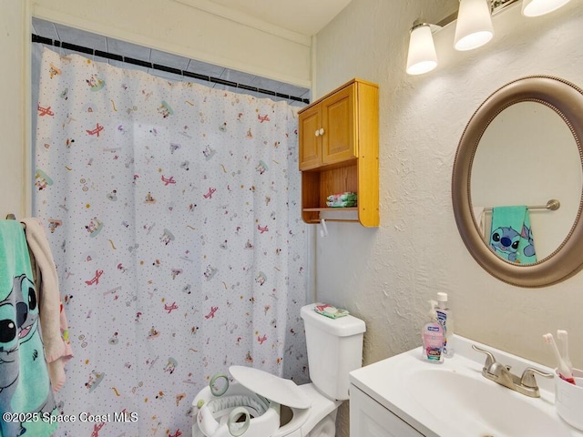 full bathroom featuring toilet, vanity, a shower with shower curtain, and a textured wall