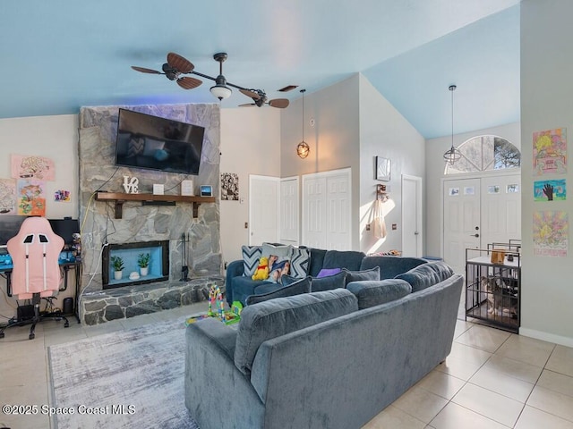 living area featuring a ceiling fan, baseboards, high vaulted ceiling, a fireplace, and tile patterned floors