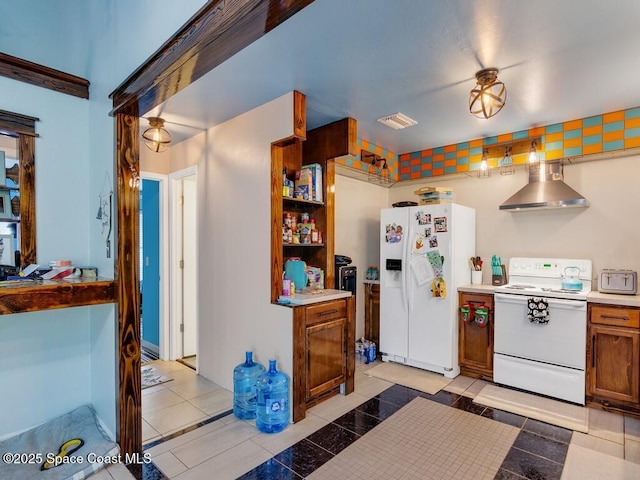 kitchen featuring white appliances, light tile patterned floors, visible vents, wall chimney range hood, and brown cabinets