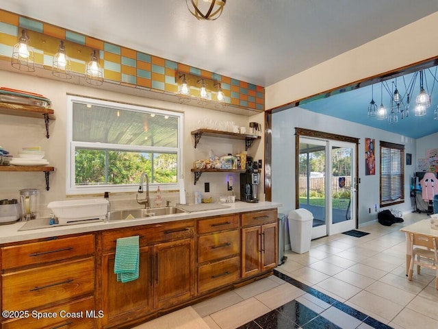 kitchen with open shelves, light countertops, brown cabinets, light tile patterned flooring, and a sink