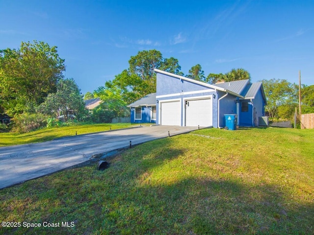 view of front of home with metal roof, an attached garage, concrete driveway, and a front lawn