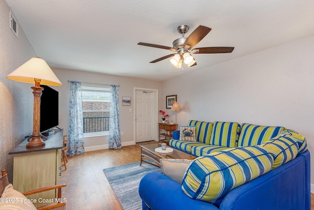 living area featuring visible vents, baseboards, wood finished floors, and a ceiling fan