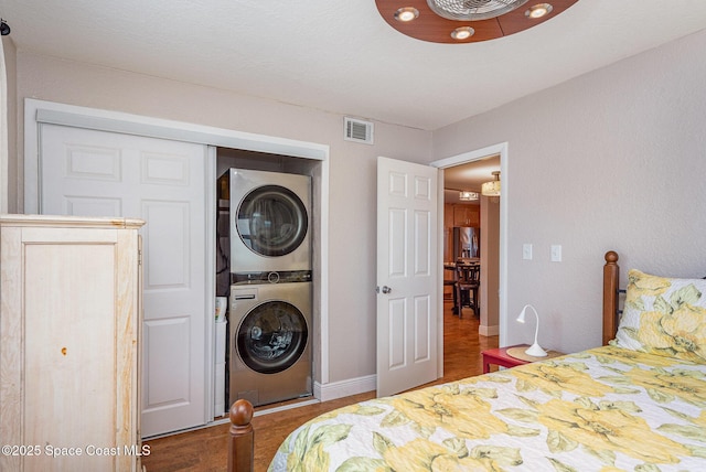 bedroom with stacked washer / drying machine, visible vents, a closet, and baseboards