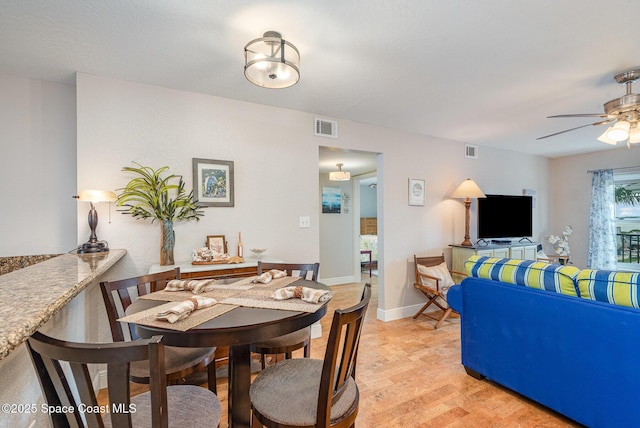 dining area featuring light wood-type flooring, visible vents, baseboards, and ceiling fan