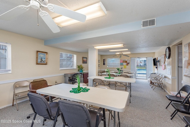 dining area featuring visible vents, baseboards, carpet, ceiling fan, and a textured ceiling