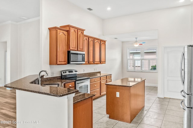 3980 Funston Cir, Melbourne, FL 32940 - kitchen featuring a peninsula, a center island, a sink, dark stone counters, and appliances with stainless steel finishes