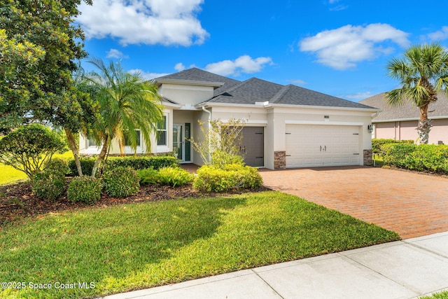 3980 Funston Cir, Melbourne, FL 32940 - view of front facade featuring an attached garage, stone siding, stucco siding, a front lawn, and decorative driveway