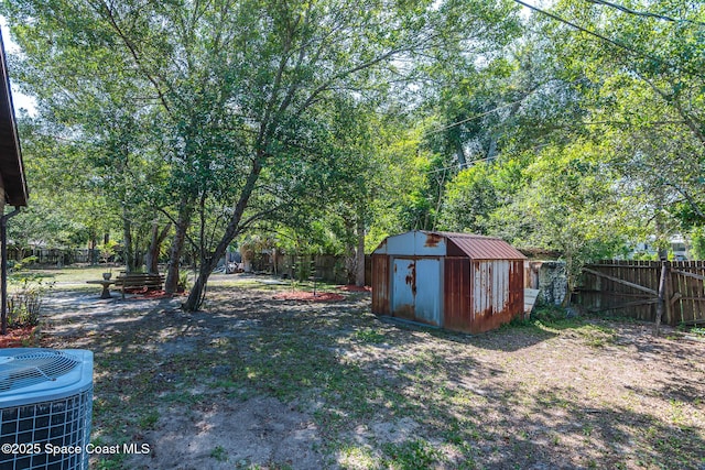 view of yard featuring a storage shed, a fenced backyard, an outdoor structure, and central AC unit