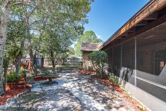 view of patio / terrace with a shed, an outdoor structure, fence, and a sunroom