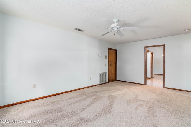 spare room with light carpet, baseboards, a ceiling fan, and visible vents
