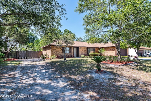 ranch-style house with an attached garage, gravel driveway, fence, and brick siding