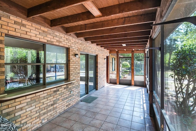 unfurnished sunroom featuring beam ceiling