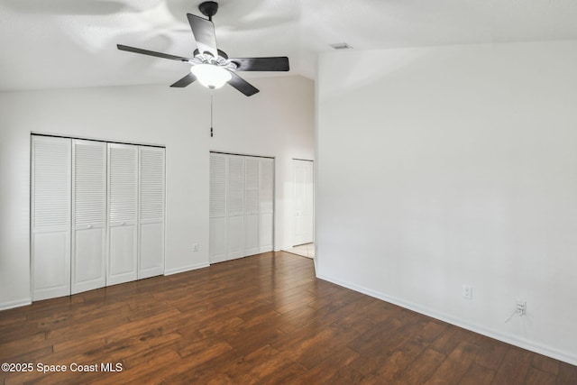 unfurnished bedroom with high vaulted ceiling, hardwood / wood-style floors, two closets, baseboards, and visible vents