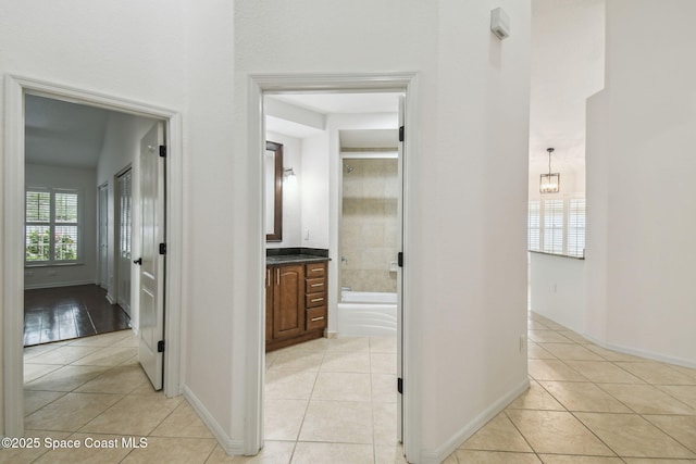 corridor featuring baseboards and light tile patterned floors