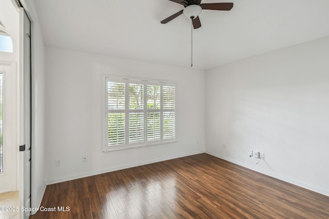 spare room featuring baseboards, wood finished floors, and ceiling fan