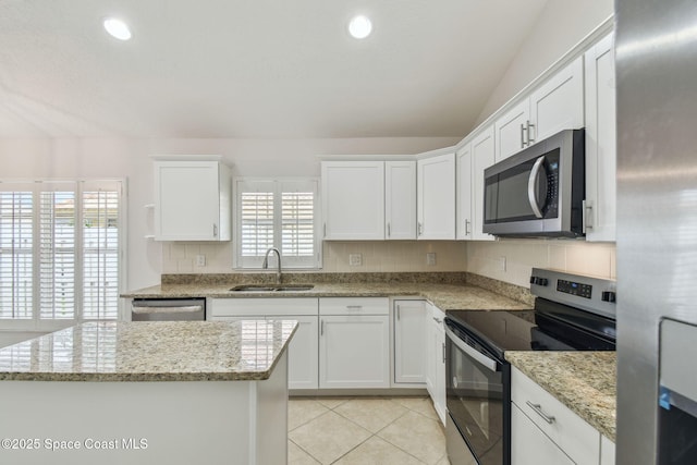 kitchen featuring light tile patterned floors, a sink, tasteful backsplash, appliances with stainless steel finishes, and white cabinetry