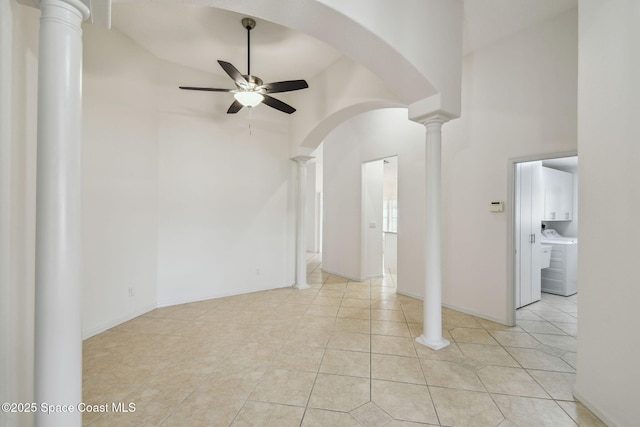 empty room featuring light tile patterned flooring, decorative columns, high vaulted ceiling, ceiling fan, and washer and dryer