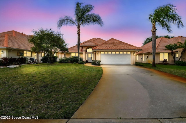 mediterranean / spanish house with a tile roof, concrete driveway, a garage, a front yard, and stucco siding