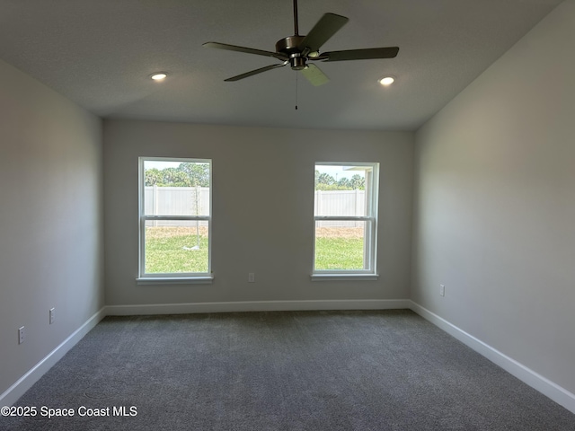 empty room featuring ceiling fan, baseboards, and dark colored carpet