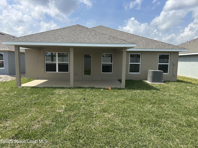 rear view of house with stucco siding, a patio, a lawn, and central AC