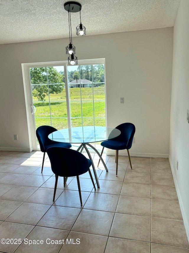 dining room with light tile patterned floors, baseboards, and a textured ceiling