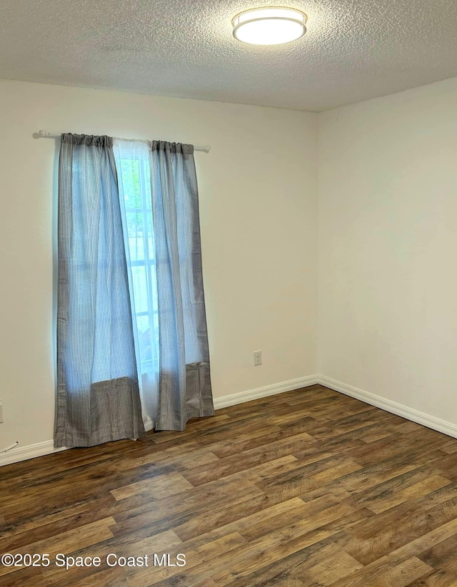 unfurnished room with wood finished floors, baseboards, and a textured ceiling