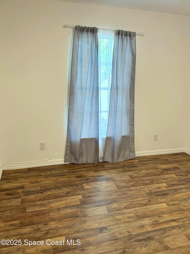 empty room featuring wood finished floors and baseboards