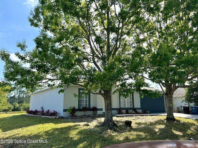 view of front of property with stucco siding, driveway, a garage, and a front yard