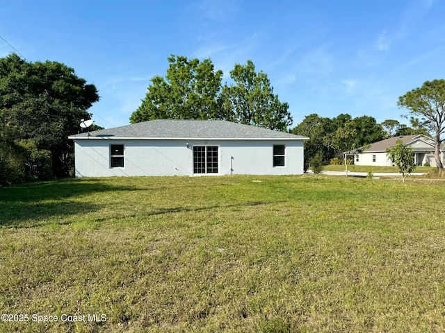 back of property featuring stucco siding and a lawn