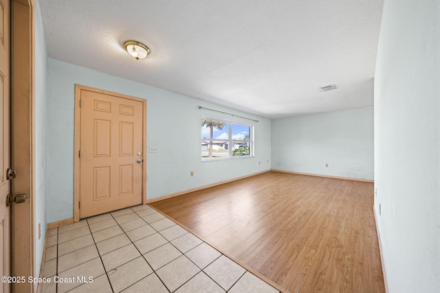 foyer featuring visible vents, baseboards, light wood-style floors, and a textured ceiling