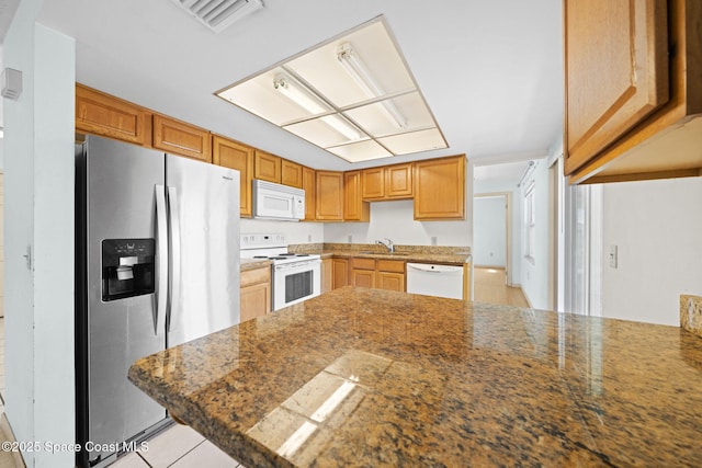 kitchen with white appliances, light tile patterned floors, visible vents, a peninsula, and a sink