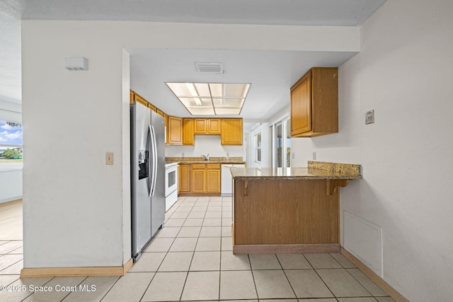 kitchen with white appliances, light tile patterned floors, visible vents, a peninsula, and a sink