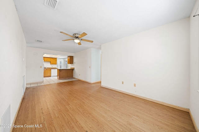 unfurnished living room with light wood-style flooring, a ceiling fan, visible vents, and baseboards