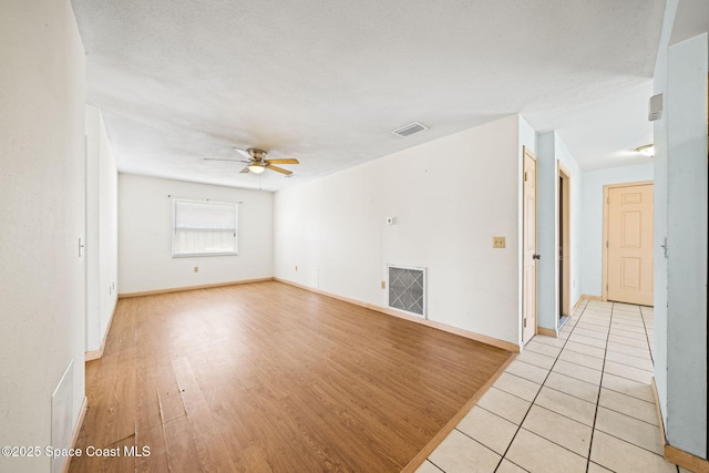 spare room featuring baseboards, visible vents, light wood finished floors, and ceiling fan