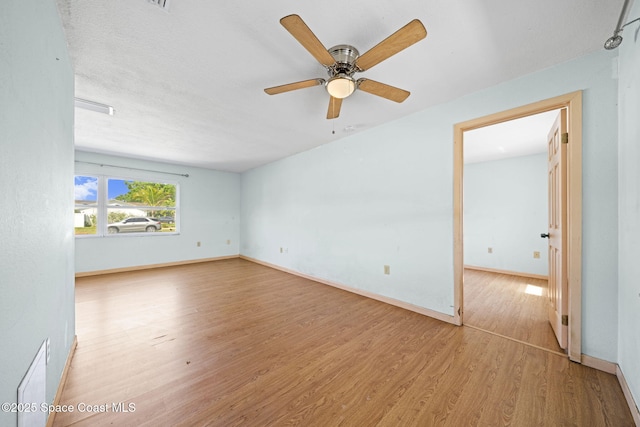 unfurnished room with a ceiling fan, wood finished floors, and baseboards