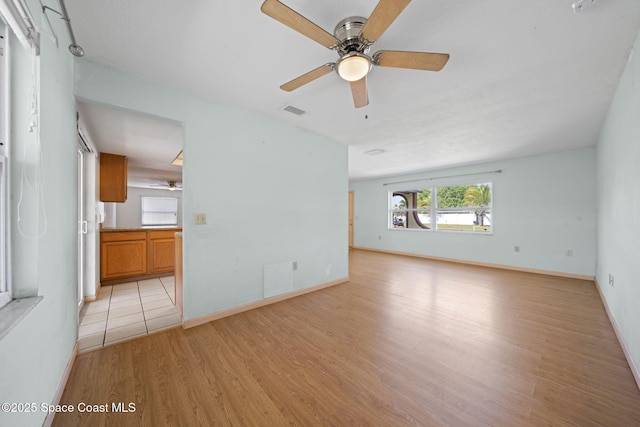 unfurnished living room featuring visible vents, light wood-style flooring, baseboards, and ceiling fan