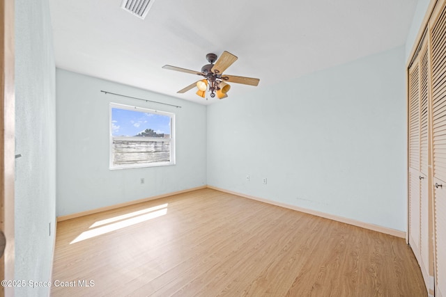 unfurnished bedroom featuring a closet, visible vents, baseboards, and wood finished floors