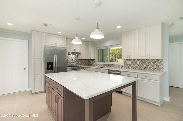 kitchen with visible vents, under cabinet range hood, a sink, stainless steel appliances, and crown molding