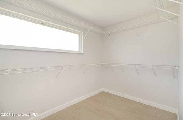 walk in closet with light wood-style flooring