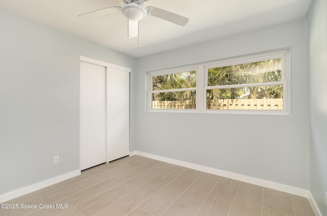 unfurnished bedroom featuring multiple windows, baseboards, a closet, and wood finish floors