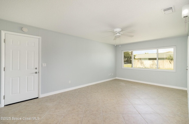 empty room with light tile patterned floors, visible vents, baseboards, and a ceiling fan