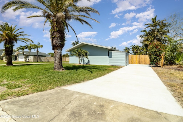 view of side of home with stucco siding, a lawn, driveway, and fence