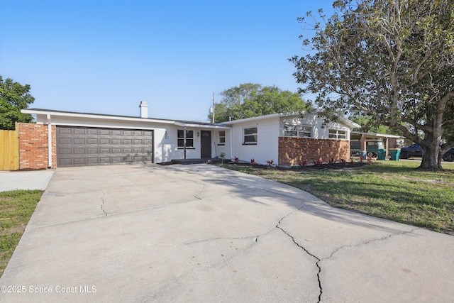 view of front facade featuring brick siding, an attached garage, driveway, and a front yard