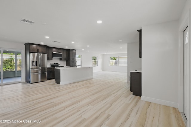 kitchen featuring visible vents, light wood finished floors, light countertops, appliances with stainless steel finishes, and open floor plan