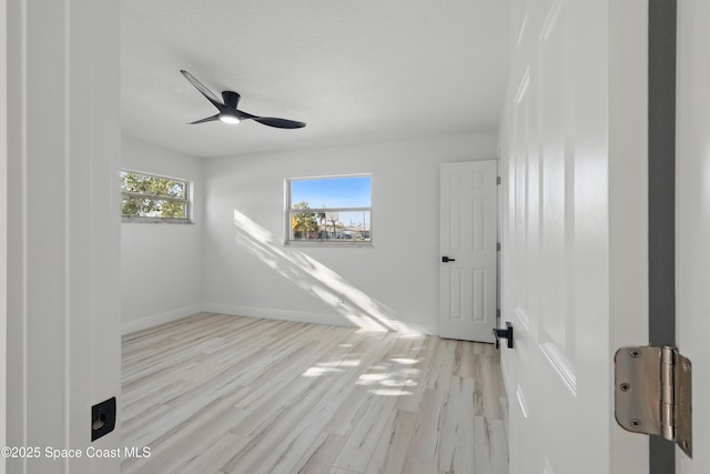 spare room featuring a textured ceiling, baseboards, a ceiling fan, and wood finished floors