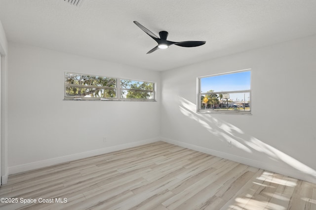 unfurnished room with a textured ceiling, a ceiling fan, baseboards, and wood finished floors