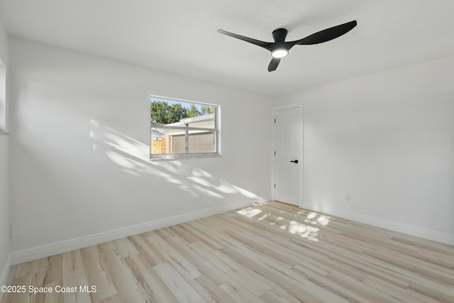 spare room with a textured ceiling, a ceiling fan, baseboards, and wood finished floors