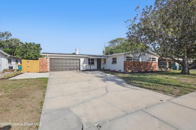 mid-century inspired home with a front lawn, fence, concrete driveway, an attached garage, and a gate